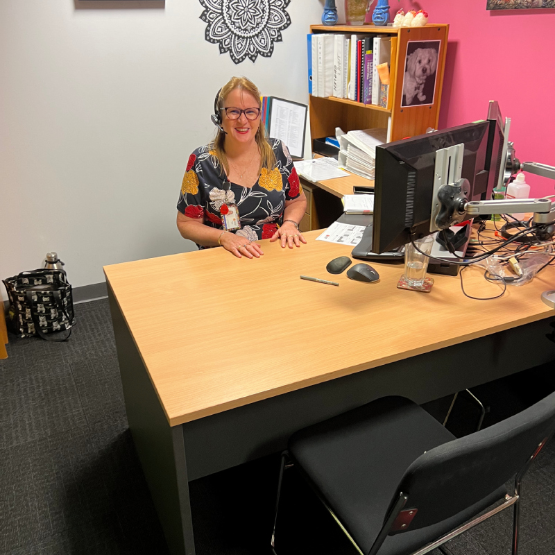 A smiling woman sitting behind her office desk.